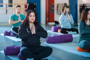 Flera personer tränar yoga på yogamattor.
