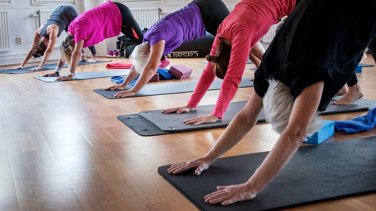 Flera personer tränar yoga på yogamattor.