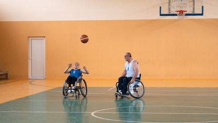 Personer som spelar rullstolsbasket i en idrottshall.