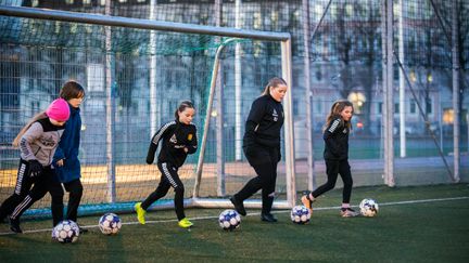 Fotbollsspelare med varsin boll  på en konstgräsplan. Ett mål i bakgrunden.