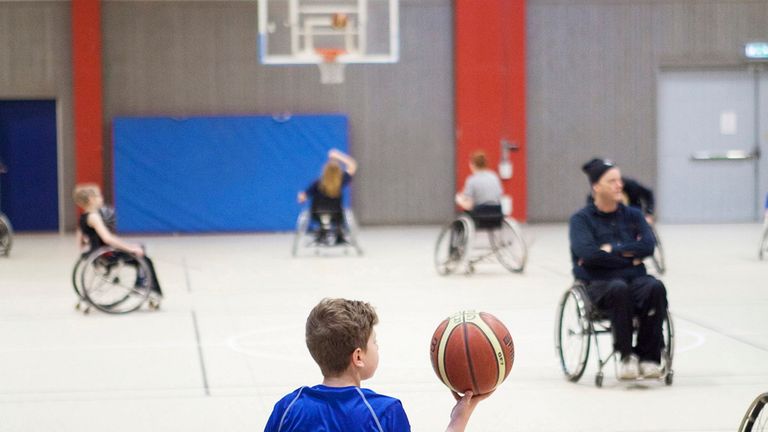 Flera personer som spelar rullstolsbasket i en sporthall.