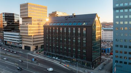 Kontorshus i rad i olika storlekar och färger, med den trafikerade Oscarsleden i förgrunden.