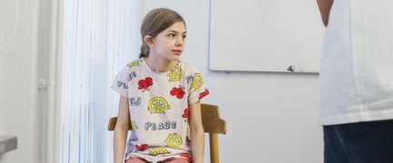 Ett barn som sitter på en stol och väntar