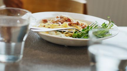 Tallrik med spagetti, sås och grön sallad på ett bord.