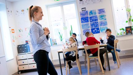 En glad lärare pratar med eleverna i klassrummet.