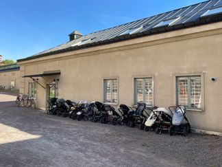 Ett gult hus med grusplan framför. Barnvagnar står utanför.