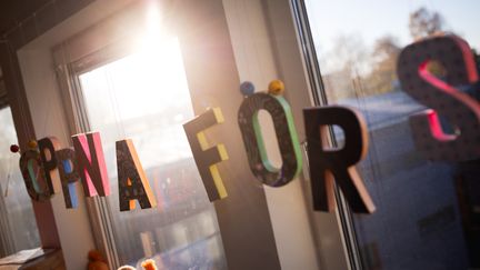 Bokstäver i olika färger hänger i ett fönster och bildar orden Öppna förskolan.