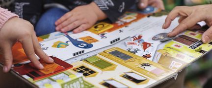 Barn och vuxenhänder pekar i en pekbok.