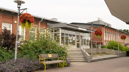 Ingång till öppna förskolan i en röd tegelbyggnad med plantering och trappa framför