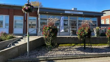 Ingång till öppna förskolan i en röd tegelbyggnad med plantering och trappa framför