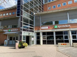 En röd tegelbyggnad med ingång i glas.