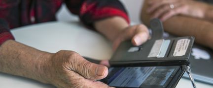 Ett foto av händer som håller i en mobiltelefon i ett plånboksfodral.