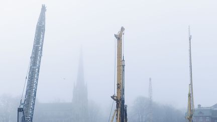 I dimman syns byggkranar och i bakgrunden skymtar stadsmiljö