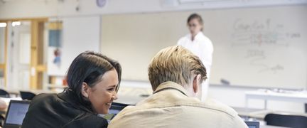 Elever under lektion. Lärare i bakgrunden.