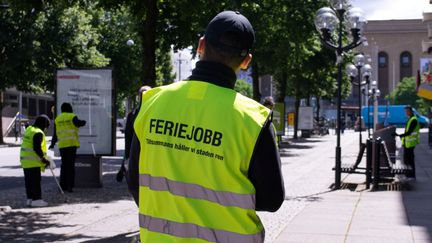 Feriejobbare med reflexvästar som städar på avenyn.