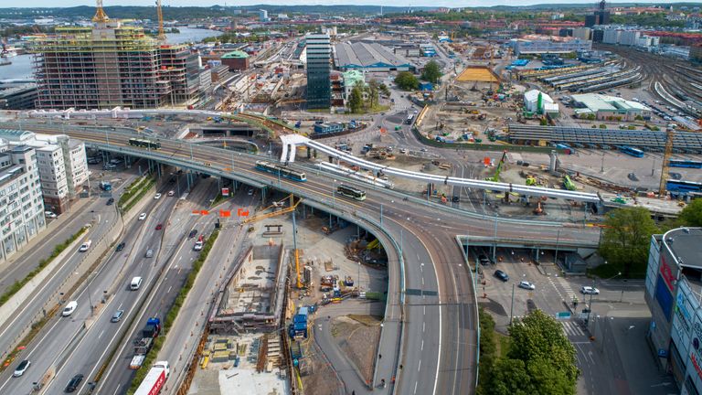 Drönarbild över bygget av Hisingsbrons kollektivtrafikbro och omgivande vägar som trafikeras av såväl bilar, lastbilar som bussar och spårvagnar.