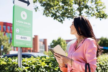 En person använder sin mobil för att betala för laddplats.