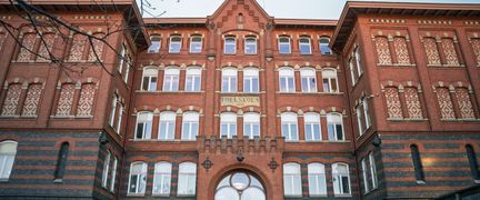 En stor skolbyggnad i rött tegel med en texten Folkskola 1897 på fasaden.