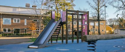 En skolgård med rutschkana och klätterställning.