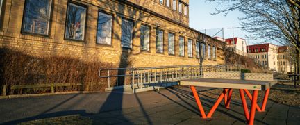 Ett pingisbord framför Santosskolan med några byggnader och träd i bakgrunden.