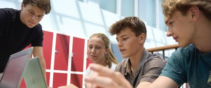 Fyra elever som fokuserar på ett gemensamt arbete på en datorskärm. Foto av Welcom