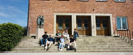 Foto av elever som sitter på trappan utanför skolbyggnaden. Foto av Welcom