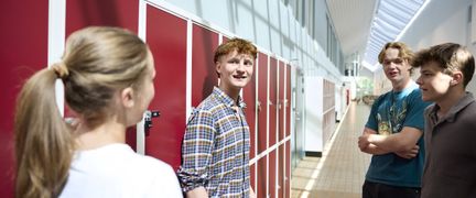 Fyra elever som socialiserar i skolkorridoren. - Foto av Welcom