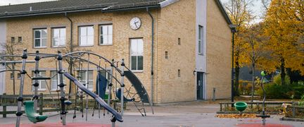 En skolgård framför en skolbyggnad med en klocka på.