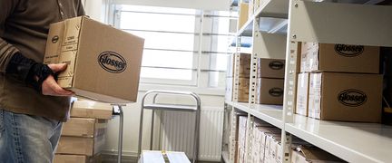 En person bär på en låda i en lagerlokal.