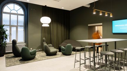 Loungerum med gröna sittfåtöljer och ett barbord med stolar