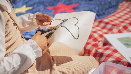 Barnhänder klipper i ett papper med en fjäril på.