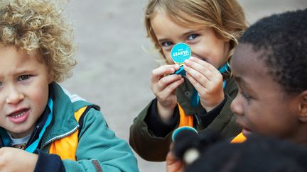 Tre barn där ett av barnen håller upp en medalj