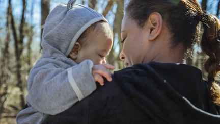 En förälder som håller sin bebis på ena armen.