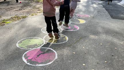 Barn hoppar i färgglada cirklar som är målade på marken.