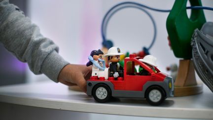 ett barn som sitter och två barn som står i bakgrunden och klappar