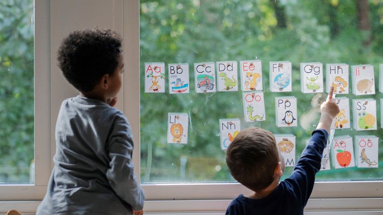 Två barn vid ett fönster med uppsatta teckningar 