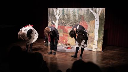 Tre personer på en scen bugar framför publiken.