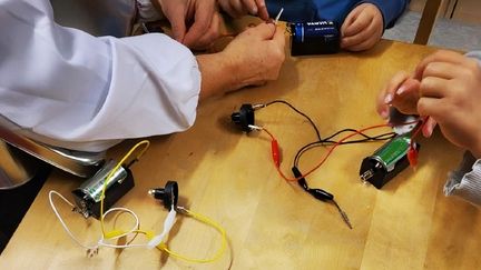 Flera par händer bygger elkretsar med batterier i.