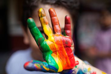 En hand som är full av målarfärg i regnbågens mönster.