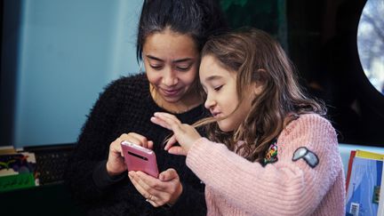 Kvinna och flicka som tittar på en mobiltelefon