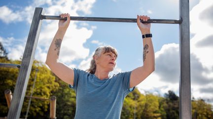 Kvinna som tränar på utomhusgym i vårsolen. 