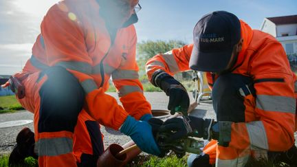 Två personer i varselkläder lagar ett rör.