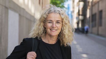Person med blont lockigt hår som ler.