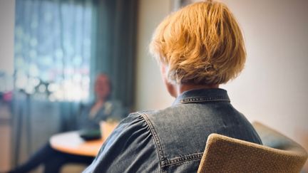 Kvinna som sitter i en stol med ryyggen mot dig. Foto: Elin Bäcklin