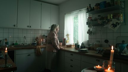 Kvinna som står vid en diskbänk i mörker.