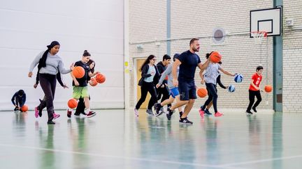 Ungdomar som spelar basket i en idrottshall.
