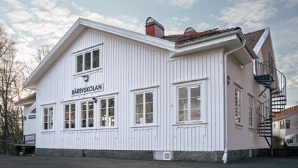 En stor vit skolbyggnad i trä.