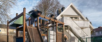 En skolgård med en lekställning på en gräsmatta.