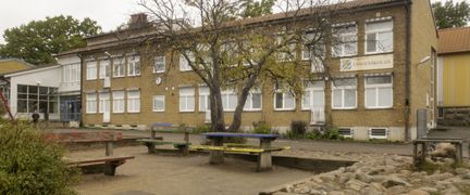 En sandlåda med bänkar och en skolbyggnad i gult tegel i bakgrunden