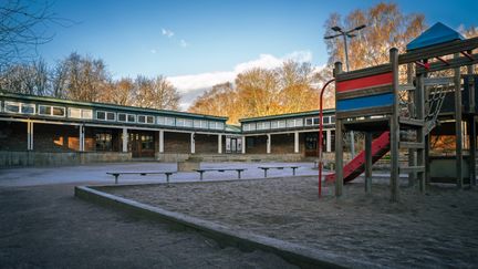 Överblick av Mossebergskolan. En lekplats med en rutschkana och några bänkar syns i bakgrunden.